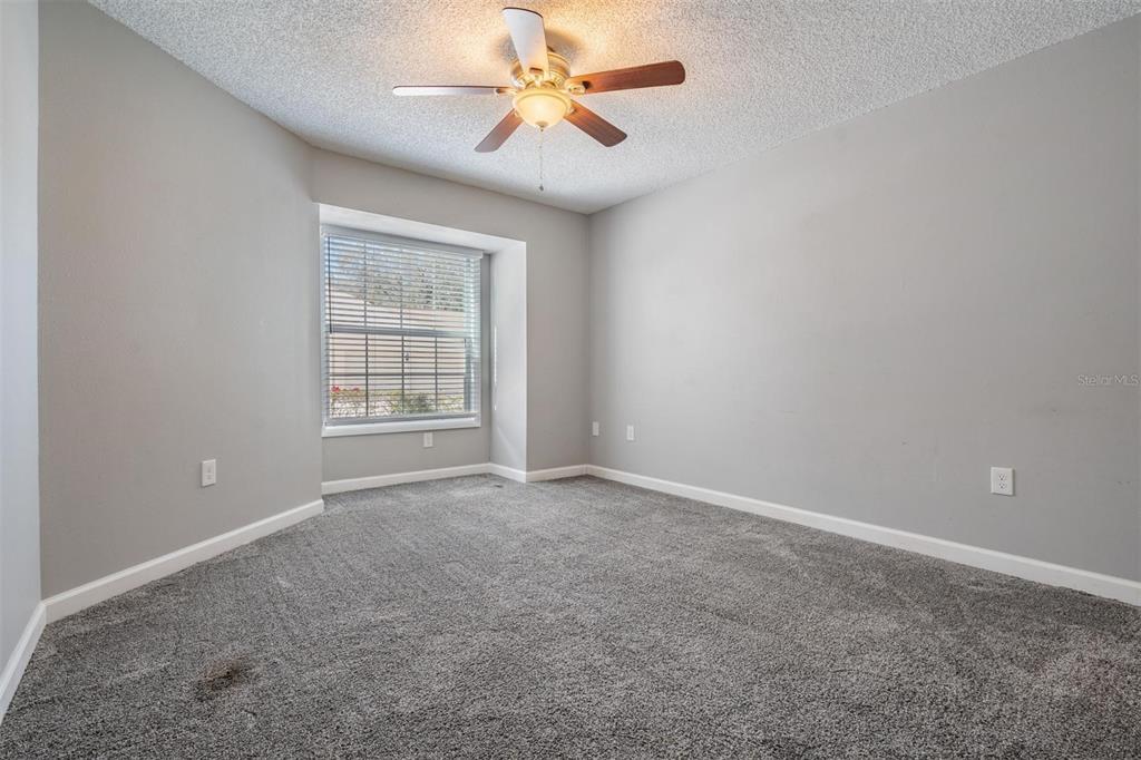 11308 Versailles Lane, Unit C Port Richey, FL 34668 - Photo 19 of 33 an empty room with windows and fan