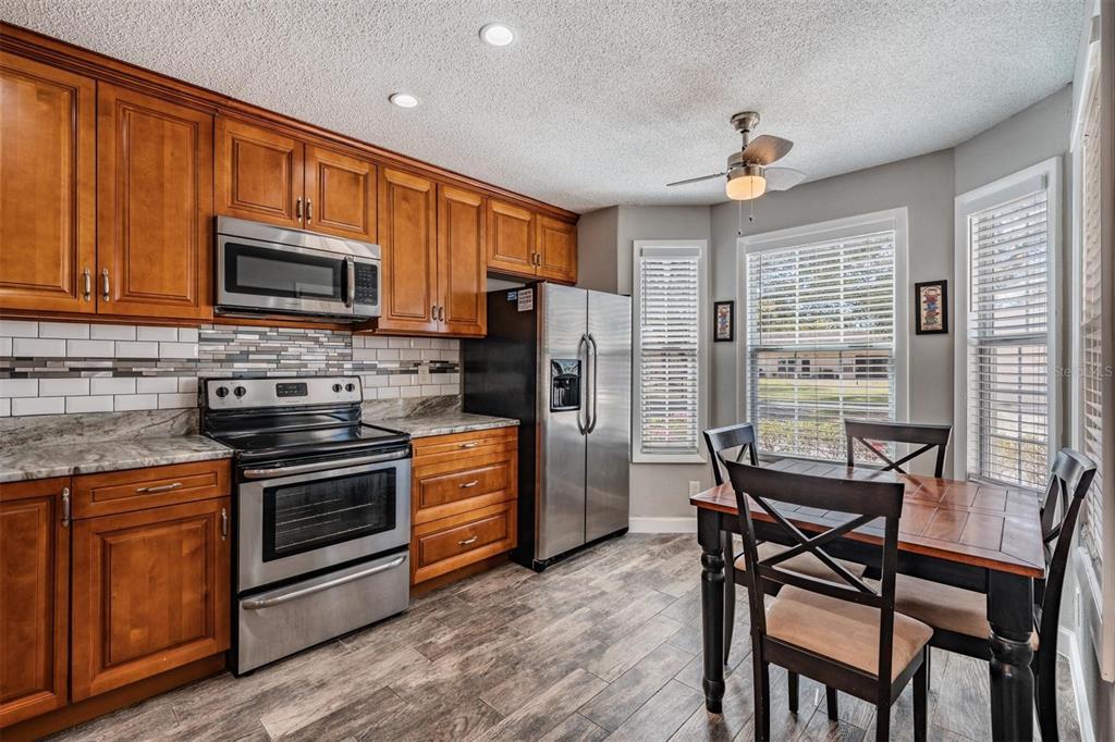 11308 Versailles Lane, Unit C Port Richey, FL 34668 - Photo 2 of 33 a kitchen with stainless steel appliances granite countertop wooden cabinets a stove top oven a sink and dishwasher