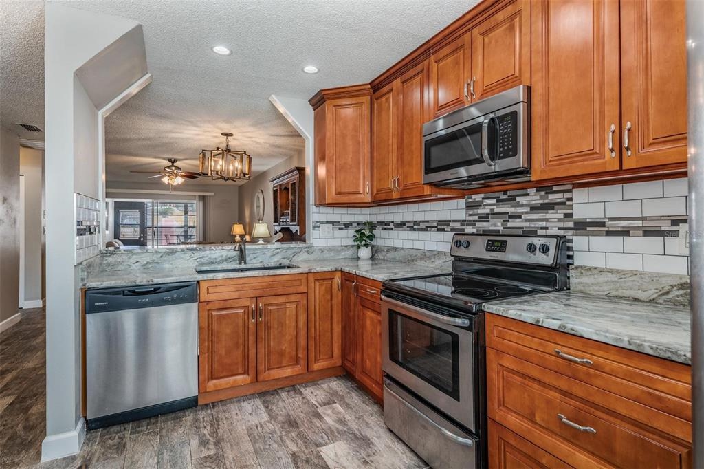 11308 Versailles Lane, Unit C Port Richey, FL 34668 - Photo 5 of 33 a kitchen with stainless steel appliances granite countertop a stove microwave and sink