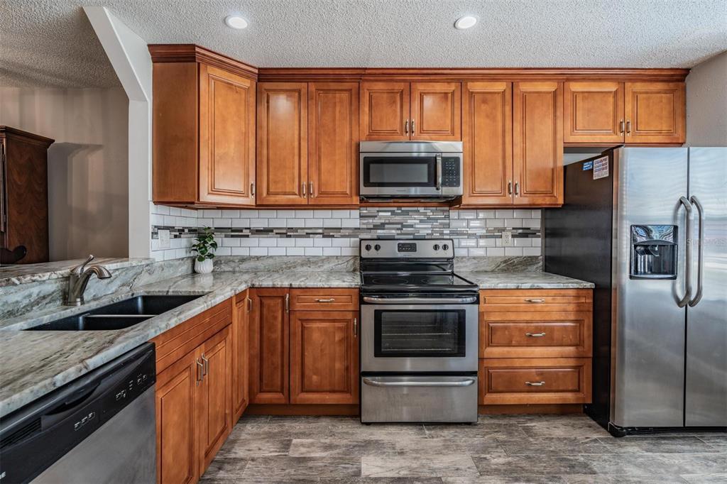 11308 Versailles Lane, Unit C Port Richey, FL 34668 - Photo 7 of 33 a kitchen with stainless steel appliances granite countertop a stove a sink and a microwave