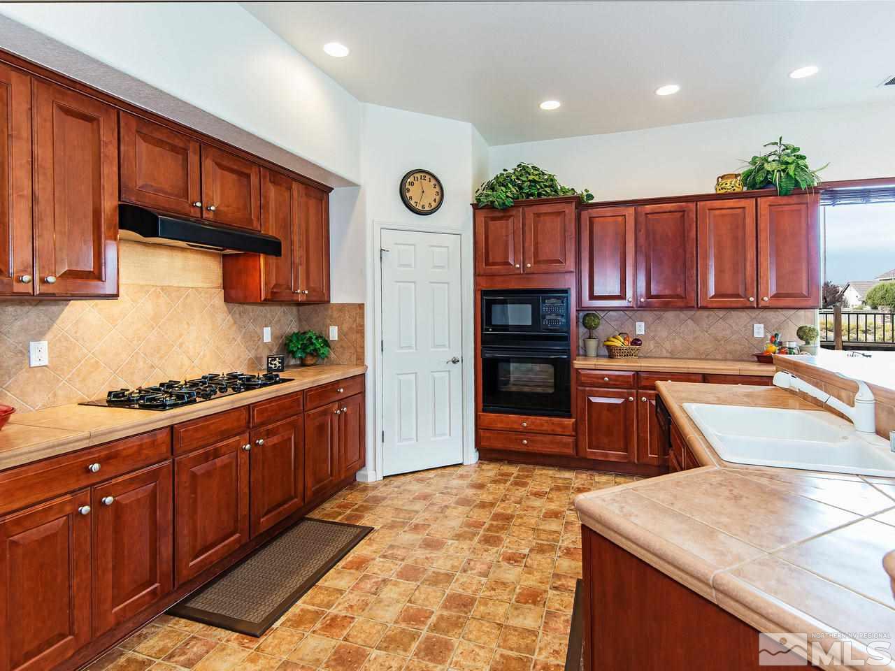 1635 Crater Court Reno, NV 89521 - Photo 8 of 25 a kitchen with stainless steel appliances granite countertop wooden cabinets a stove top oven a sink and dishwasher