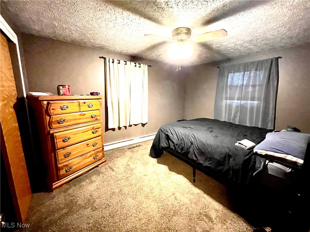 9810 Ziegler Road Hanoverton, OH 44423 - Photo 8 of 18 Bedroom featuring a baseboard radiator, carpet, ceiling fan, and a textured ceiling