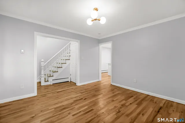 a view of an empty room with wooden floor and a ceiling fan