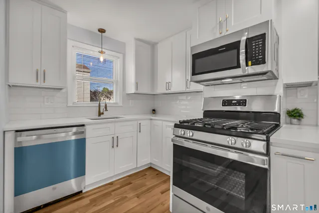 a kitchen with cabinets stainless steel appliances and wooden floor