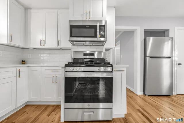 a kitchen with cabinets stainless steel appliances and wooden floor