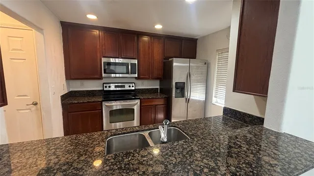 a kitchen with granite countertop a refrigerator and a stove top oven