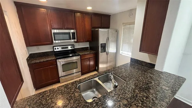 a kitchen with granite countertop a refrigerator stove and microwave