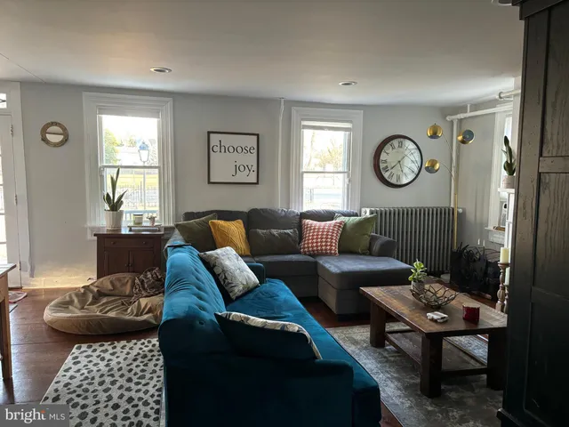 a living room with furniture a clock on wall and a window