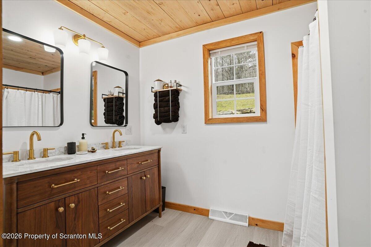 232 Starrucca Creek Road Starrucca, PA 18462 - Photo 36 of 64 a bathroom with a double vanity sink and mirror