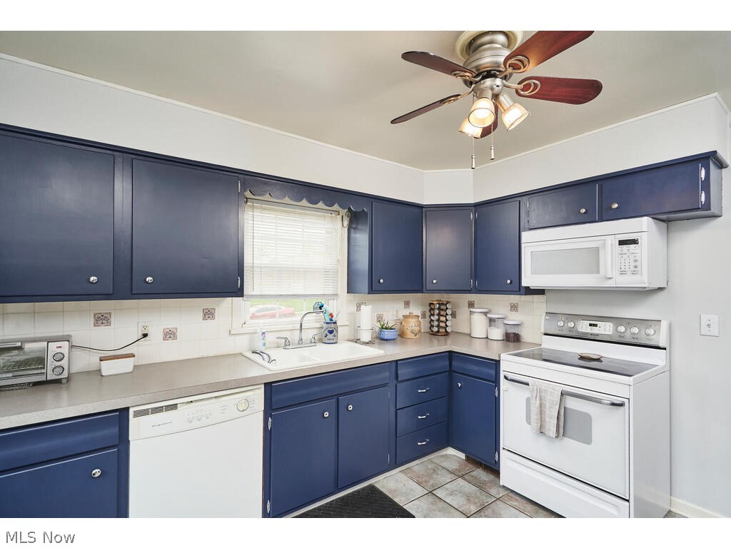563 East Wilbeth Road Akron, OH 44301 - Photo 6 of 19 Kitchen featuring ceiling fan, white appliances, sink, and blue cabinetry