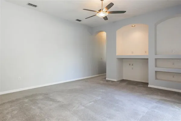 an empty room with windows and fan