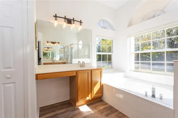 a large bathroom with a tub a sink and a large mirror next to a window