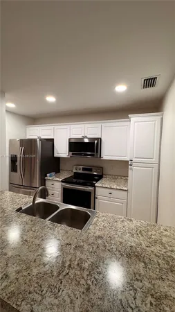 a kitchen with stainless steel appliances kitchen island granite countertop a refrigerator and a stove top oven