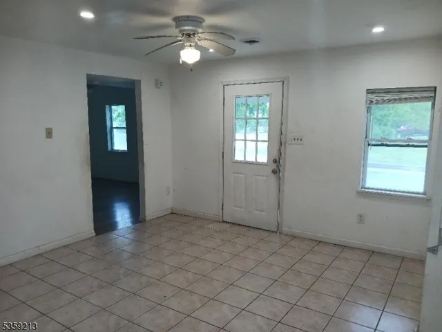 an empty room with windows and fan