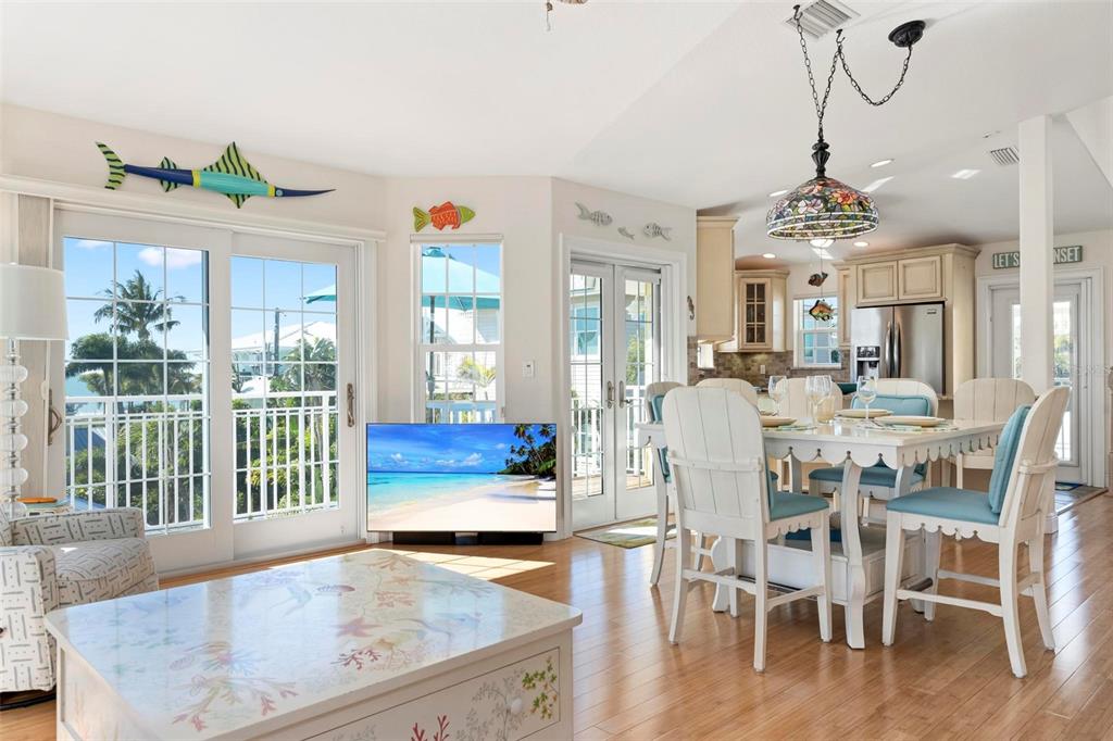 106 79th Street Holmes Beach, FL 34217 - Photo 16 of 98 a dining room with wooden floor a chandelier a wooden table and chairs
