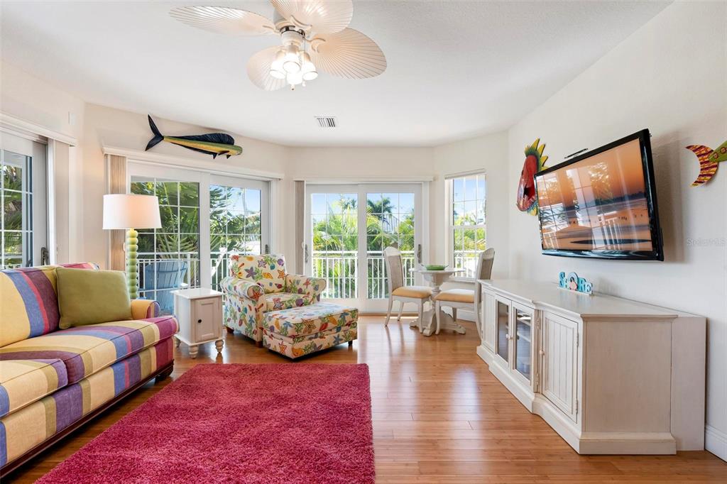 106 79th Street Holmes Beach, FL 34217 - Photo 31 of 98 a living room with furniture floor to ceiling window and a flat screen tv