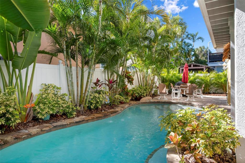 106 79th Street Holmes Beach, FL 34217 - Photo 66 of 98 a view of a swimming pool with a table and chairs potted plants and large tree