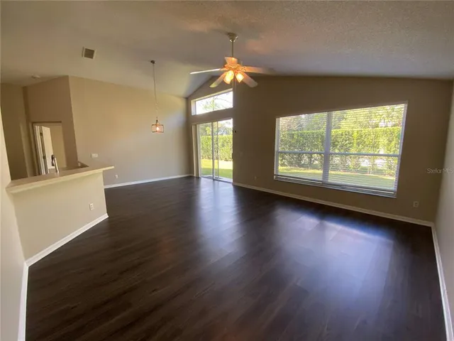 an empty room with chandelier fan and windows
