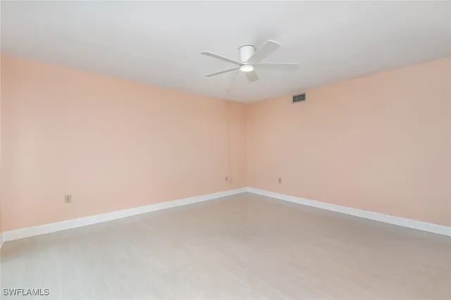 an empty room with a window and ceiling fan