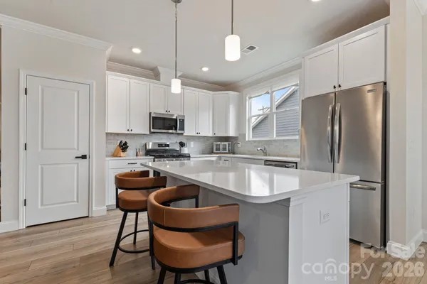 a kitchen with stainless steel appliances granite countertop a sink a stove a refrigerator and island with wooden floor