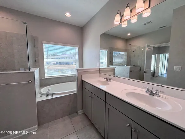 a bathroom with a tub a sink double vanity and a mirror