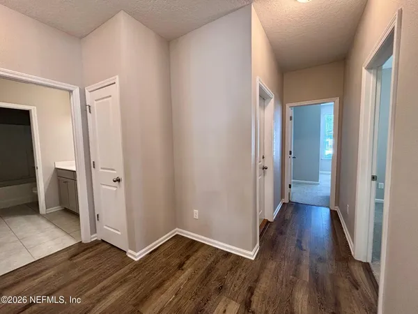 a view of a hallway with wooden floor and closet