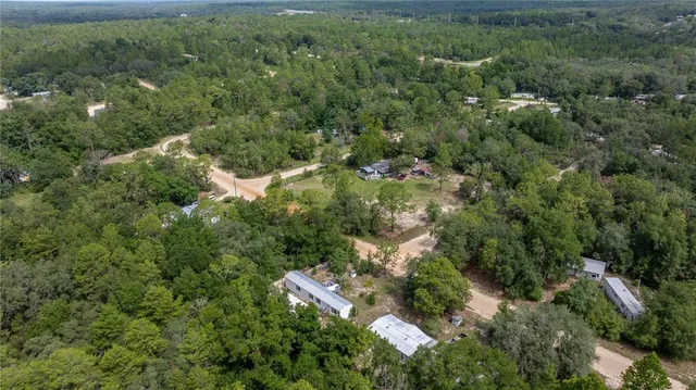 an aerial view of residential house with outdoor space and trees all around