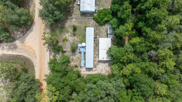 an aerial view of a house with a yard and large trees