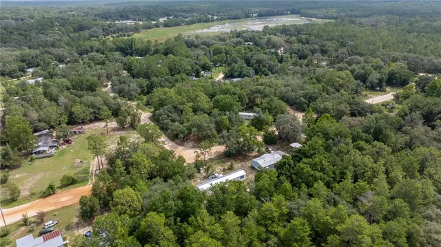 an aerial view of residential house with outdoor space and trees all around