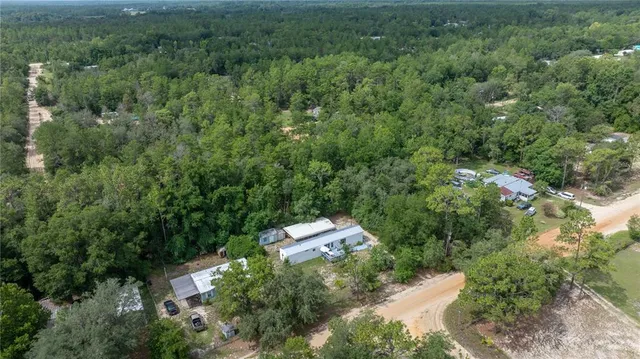 an aerial view of residential house with outdoor space and trees all around