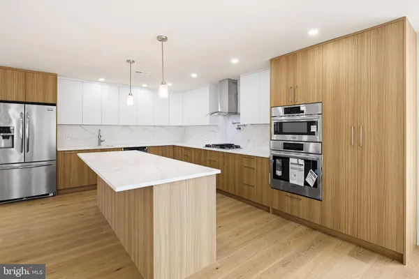 a kitchen with kitchen island granite countertop a stove top oven a sink and a refrigerator