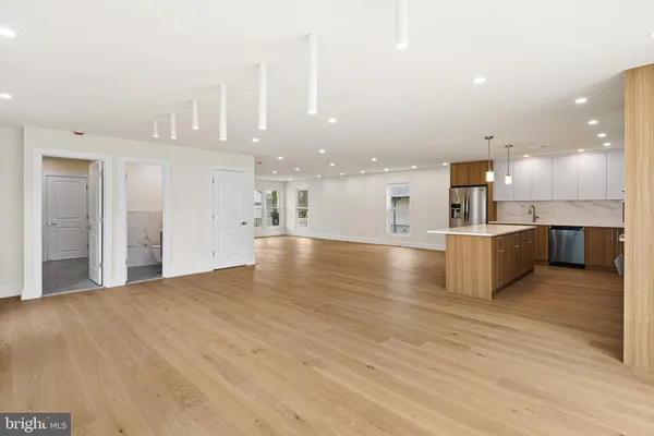 a view of a kitchen with kitchen island a sink stainless steel appliances and cabinets