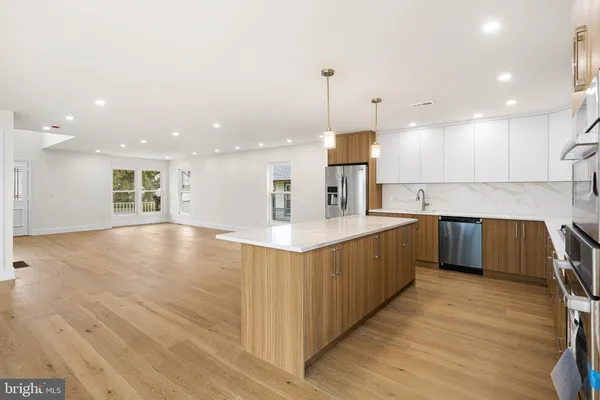 a large kitchen with stainless steel appliances kitchen island a large counter top and a wooden floors