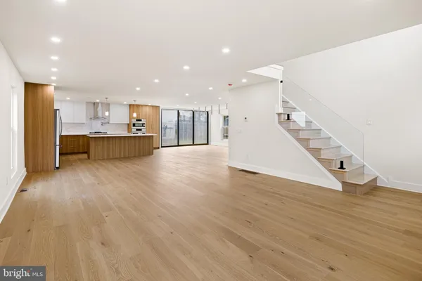 a view of a living room with kitchen and wooden floor