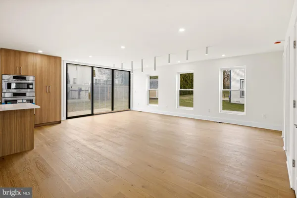 a view of an empty room with wooden floor and windows