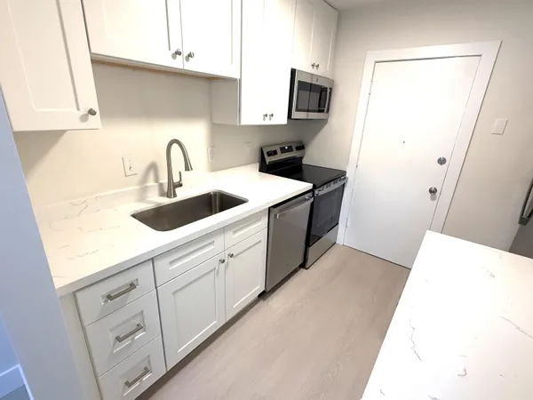 a kitchen with white cabinets and sink