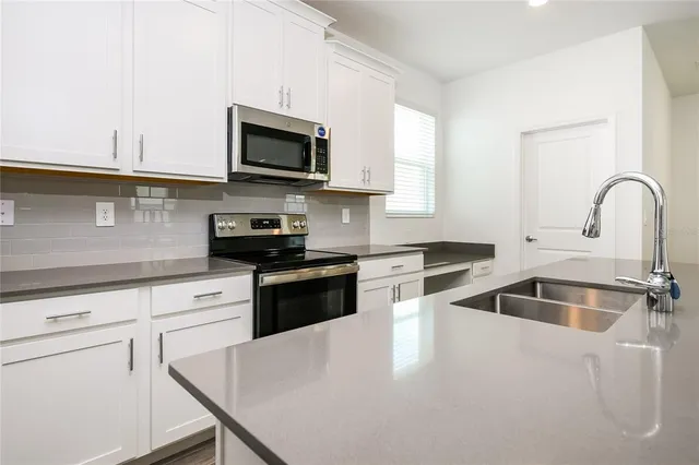 a kitchen with white cabinets a sink and a stove with wooden floor