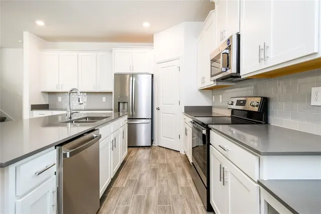 a kitchen with stainless steel appliances granite countertop a refrigerator a stove and a sink