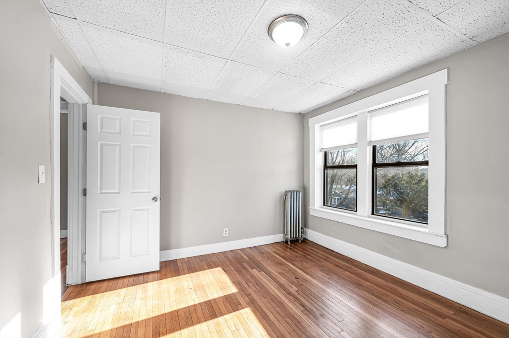 92 Woodside Terrace, Unit 3R Springfield, MA 01108 - Photo 28 of 42 an empty room with wooden floor and windows
