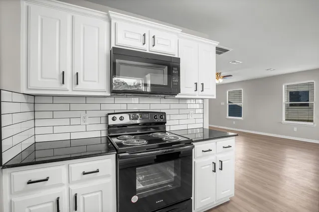 a kitchen with granite countertop a stove microwave and cabinets