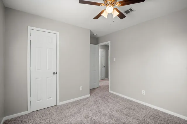a view of an empty room and chandelier fan