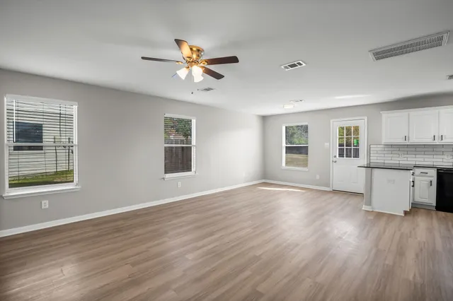 a view of an empty room with window and wooden floor