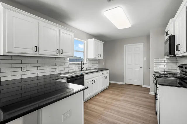 a kitchen with stainless steel appliances granite countertop a sink a stove and cabinets