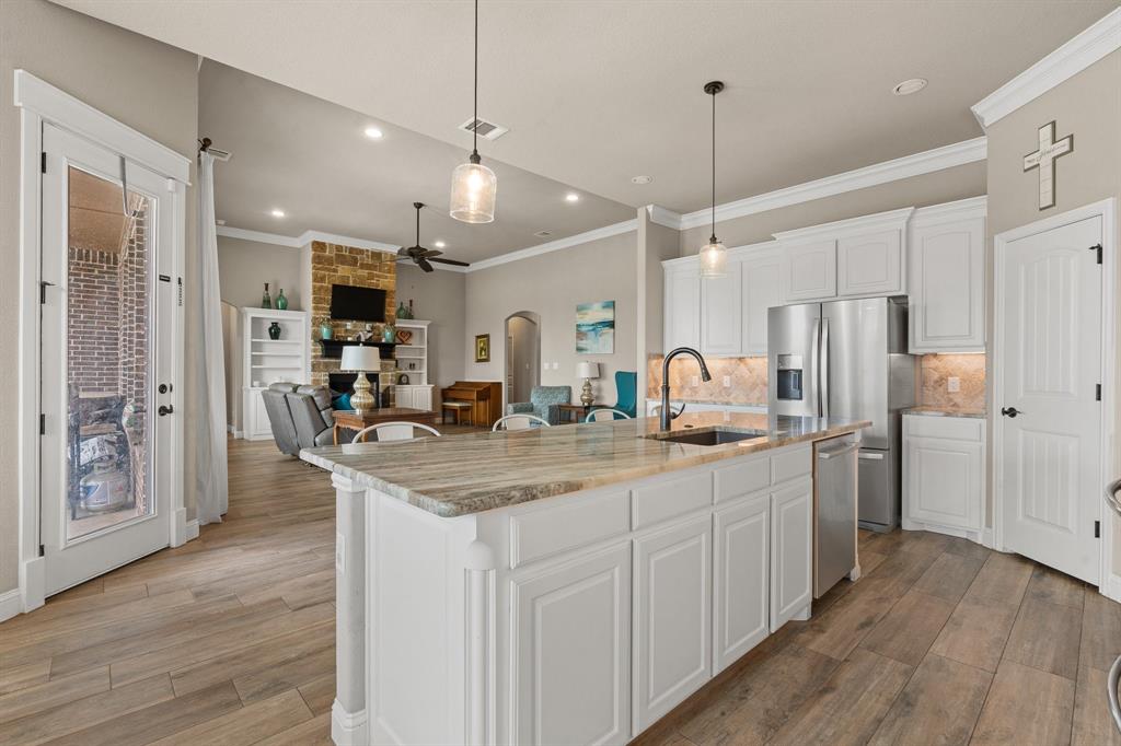 9708 Puma Trail Godley, TX 76044 - Photo 9 of 40 a kitchen with stainless steel appliances kitchen island granite countertop a refrigerator a sink dishwasher a oven and a dining table with wooden floor