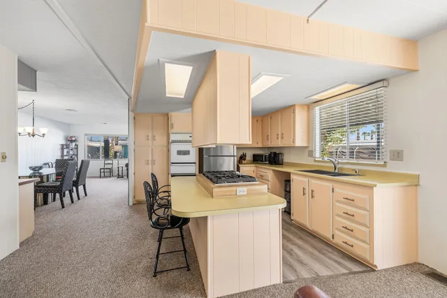 a kitchen with stainless steel appliances kitchen island granite countertop a table chairs sink and cabinets