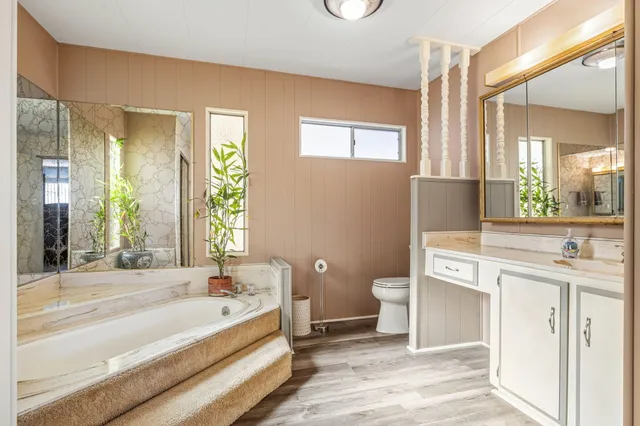 a spacious bathroom with a bathtub shower sink mirror and toilet