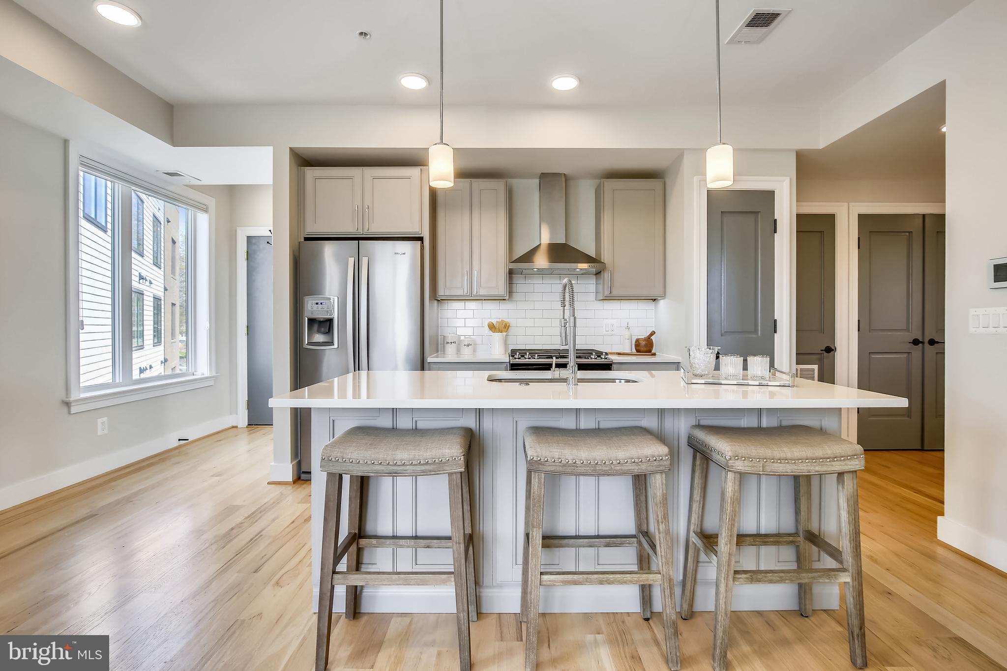 a kitchen with kitchen island granite countertop a table chairs sink and wooden floor