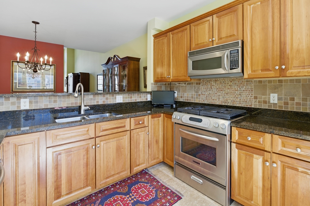 2 Powder Mill Square, Unit 2B Andover, MA 01810 - Photo 5 of 31 a kitchen with granite countertop a sink stove and microwave
