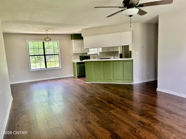 a kitchen with a wooden floor cabinets and a window