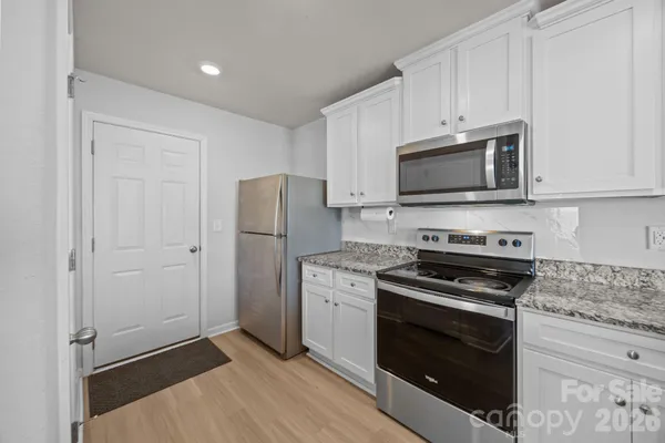 a kitchen with cabinets stainless steel appliances and a wooden floor